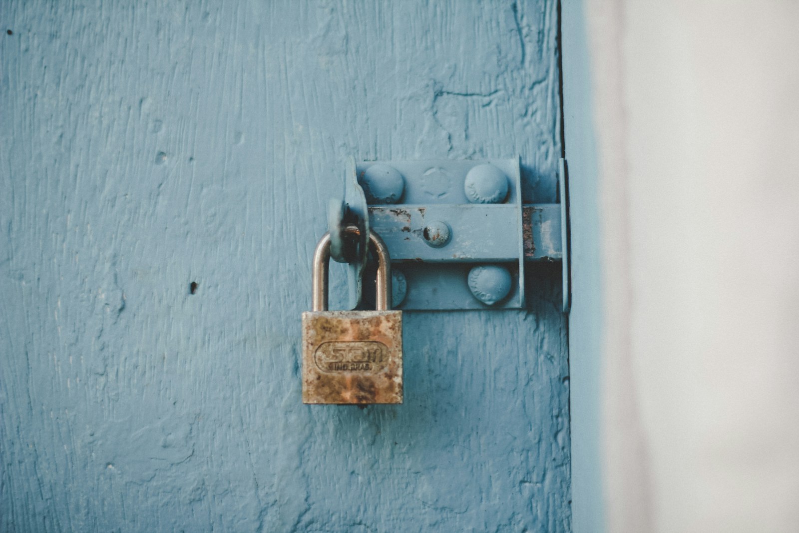 Brown padlock on blue wooden door