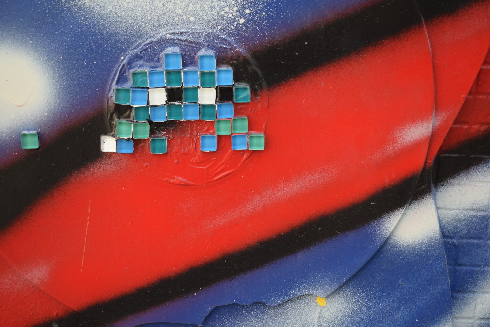 A pixelated alien figure on a graffiti-painted wall.
