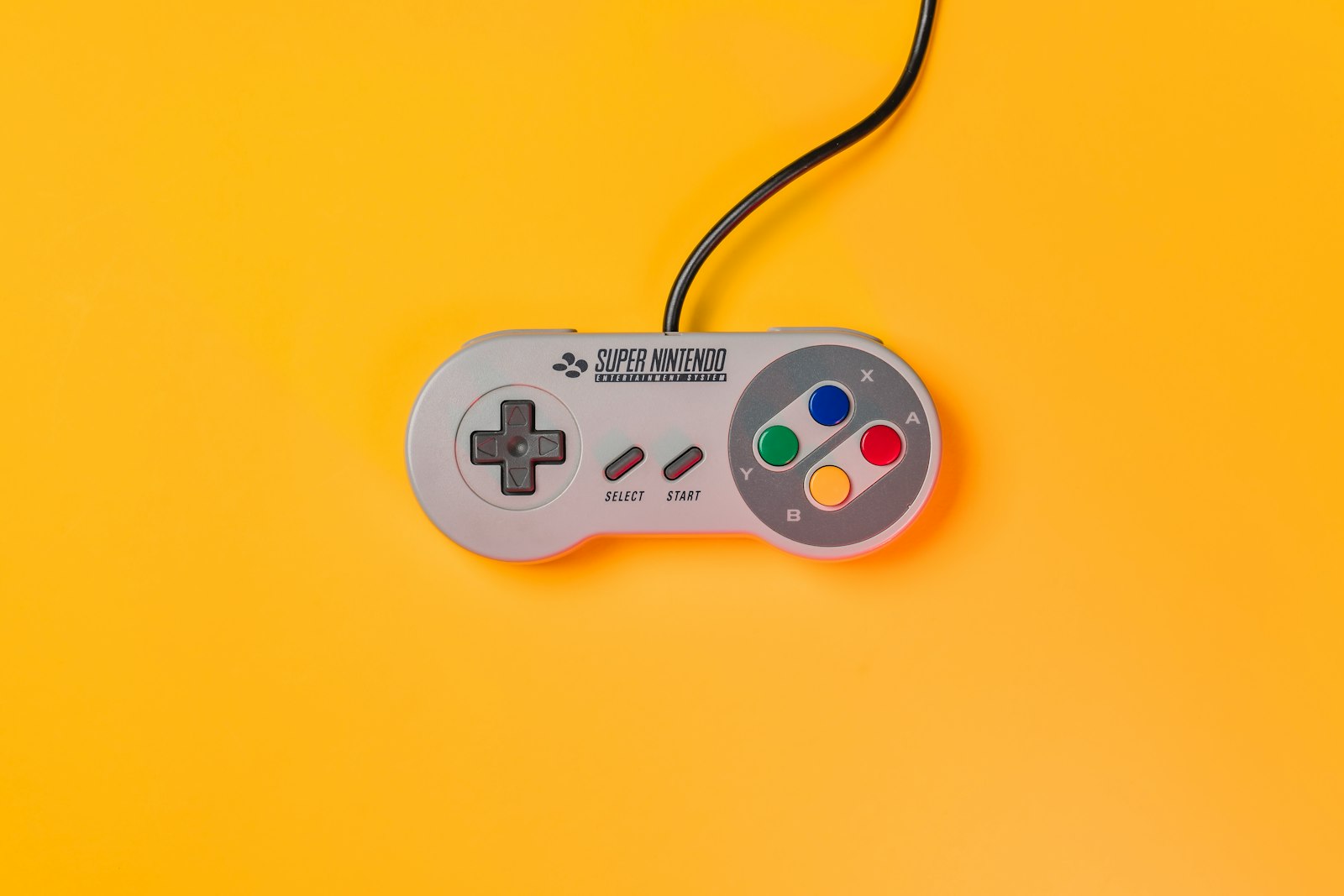White nintendo game controller on yellow surface