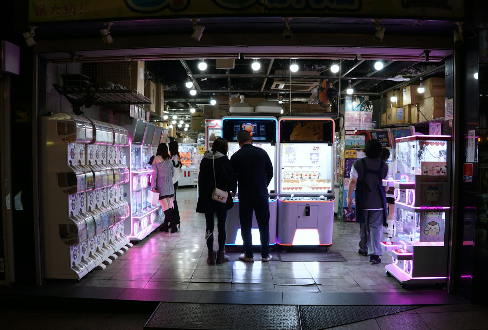 People in a brightly lit arcade at night