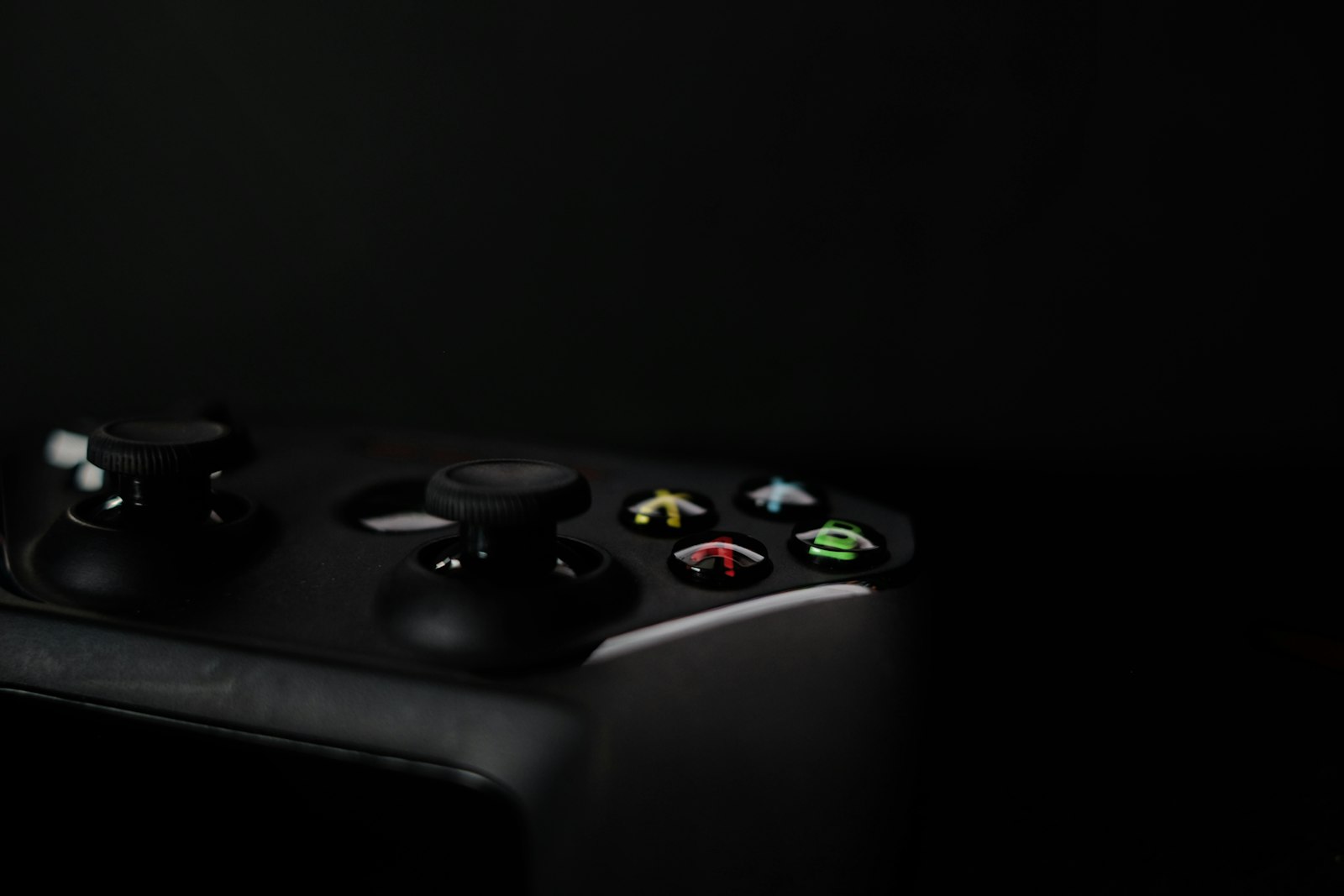 A black video game controller on a dark background