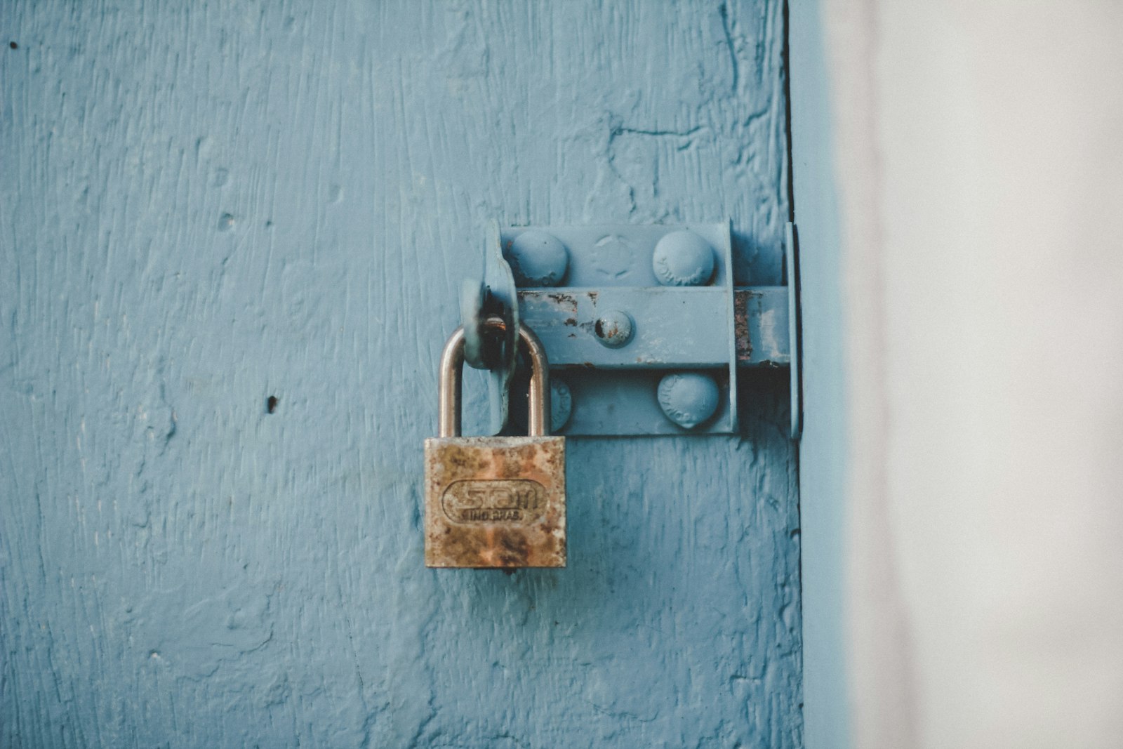Brown padlock on blue wooden door